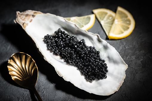Caviar negro en concha de ostra sobre fondo de pizarra negra photo