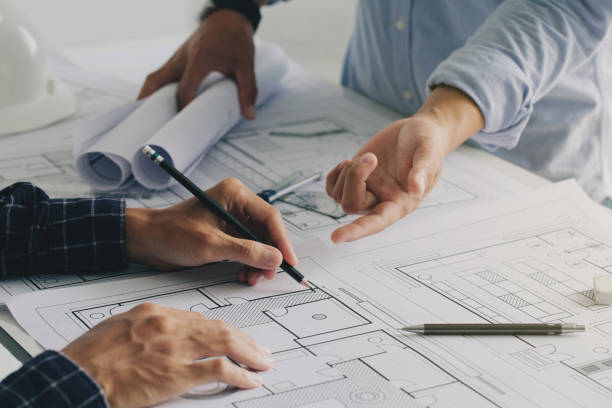 istock Two business man construction site engineers. working drawing on blueprint and discussing the floor plans over blueprint architectural plans at table in a modern office. construction concept 1330167043