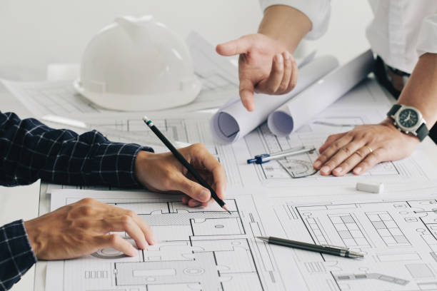 istock Two business man construction site engineers. working drawing on blueprint and discussing the floor plans over blueprint architectural plans at table in a modern office. construction concept 1330167044