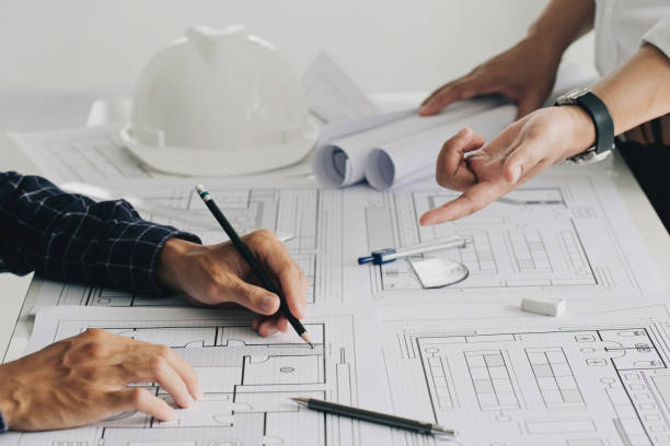 istock Two business man construction site engineers. working drawing on blueprint and discussing the floor plans over blueprint architectural plans at table in a modern office. construction concept 1330167241