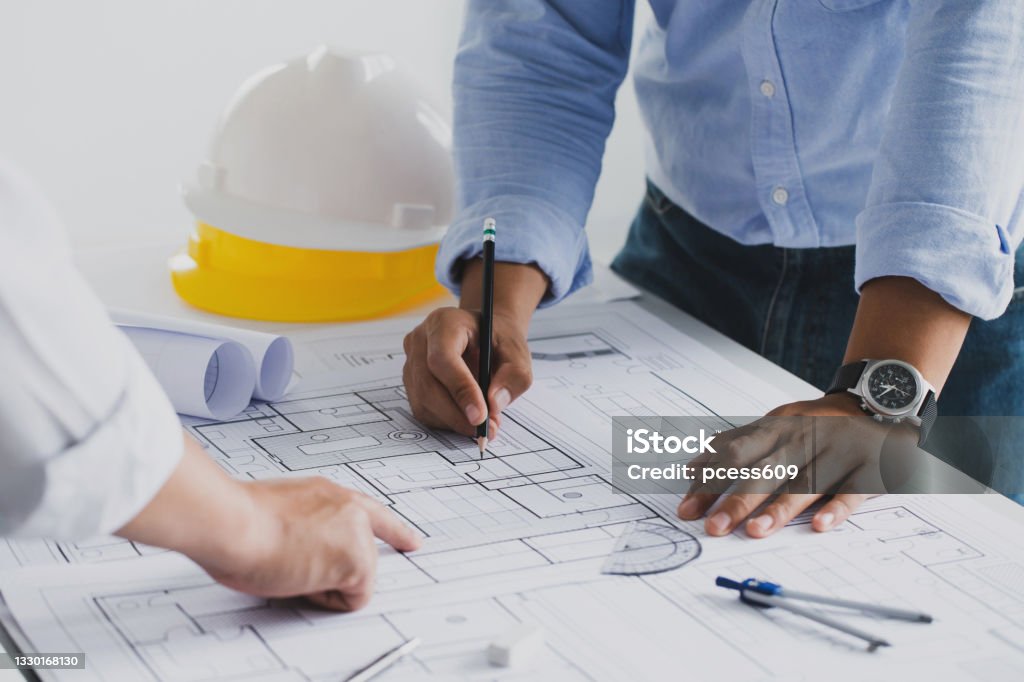 engineer meeting for an architectural project. working with partner and engineering tools working on blueprint architectural project at the construction site at desk in the office. Construction Site Stock Photo