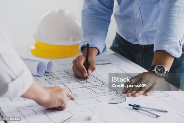 Engineer Meeting For An Architectural Project Working With Partner And Engineering Tools Working On Blueprint Architectural Project At The Construction Site At Desk In The Office Stock Photo - Download Image Now