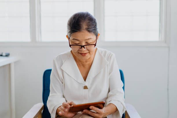 istock Smiling senior woman using smartphone at home 1330170835