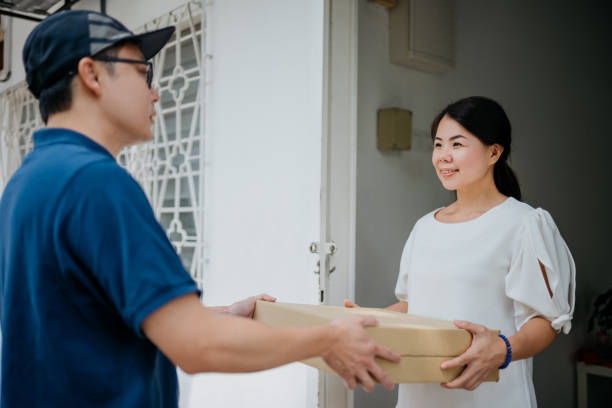 istock Young asian woman receiving a parcel from deliveryman 1330170872