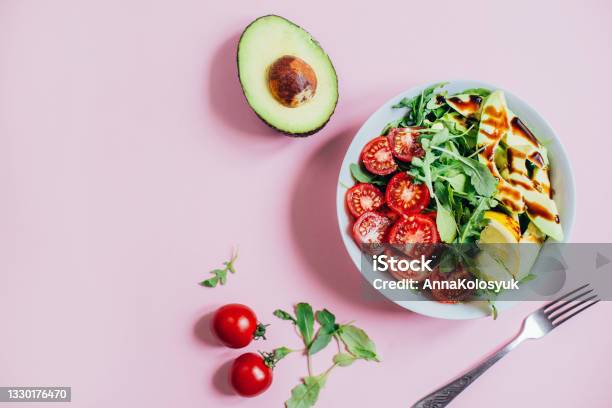 Top View Of Tomato Salad Arugula Avocado Lemon In White Plate On Pink Background Stock Photo - Download Image Now