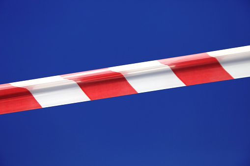 Red and white restrictive tape on the street, stretched to restrict access to this area of the street, yard. Element in criminal investigations, chronicle, news, construction work.