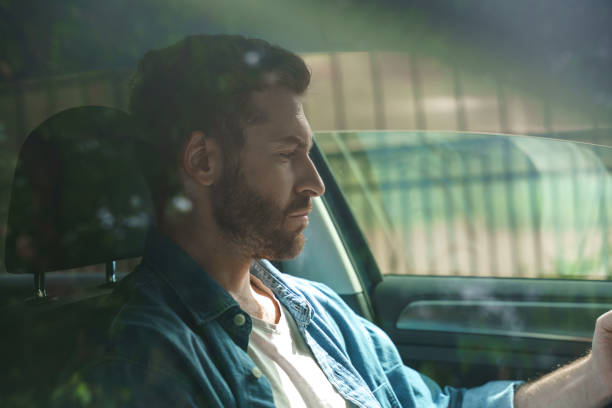 istock A profile view of a bearded serious driver, looking  in his phone, which is not in a frame, sitting on a driver's seat 1330181599