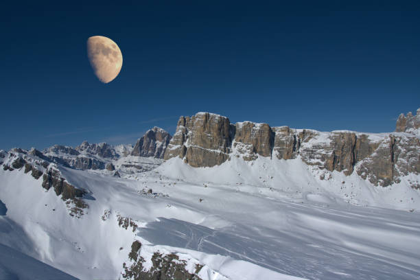 first quarter moon over italian dolomites in winter season with snow and clear sky