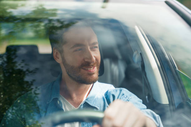 istock A male driver smiles, looking at a forest outside a car window 1330182635