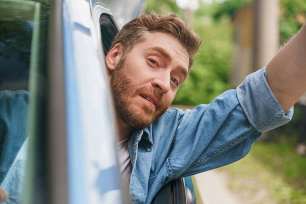 istock A middle aged man waving to someone while driving a car 1330182647