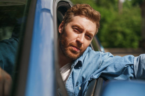 istock A serious frowning man waving to someone while driving a car 1330182654