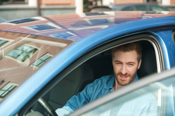 istock A handsome driver in a denim shirt is going to get off the car 1330187349