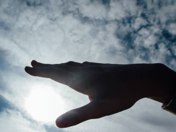 istock Hand doing gestures with the sun and cloudy sky background 1330189620