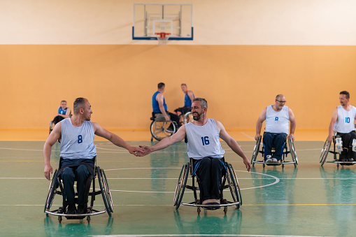 a team of war veterans in wheelchairs playing basketball, celebrating points won in a game. High five concept. High quality photo