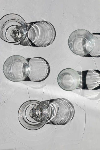 istock Glass on a grey concrete table with sunbeams and reflections 1330191504