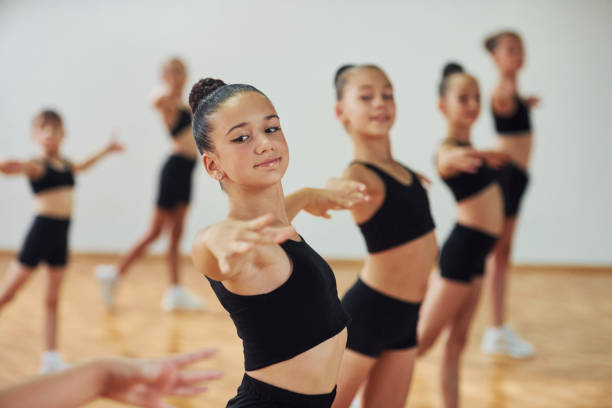 istock Standing and doing synchronised moves. Group of female kids practicing athletic exercises together indoors 1330191669