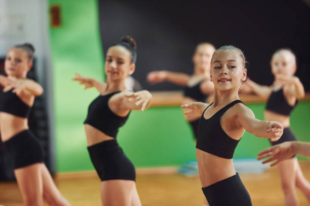 istock Standing and doing synchronised moves. Group of female kids practicing athletic exercises together indoors 1330191691