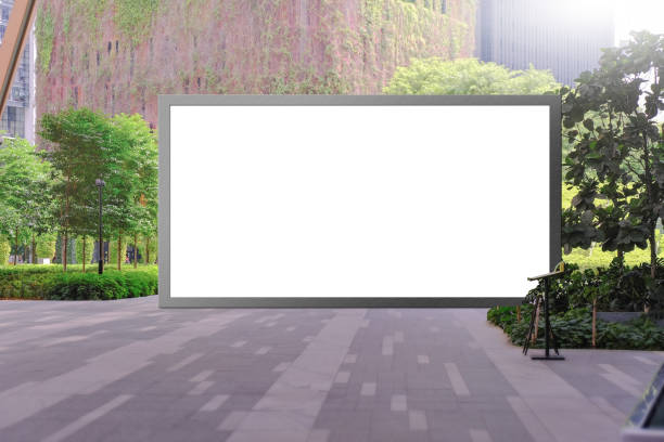 istock Blank advertising poster banner mockup in lush open air environment, empty exhibition space in foreground; large digital lightbox display screen. Billboard poster, out-of-home OOH media display space 1330197026
