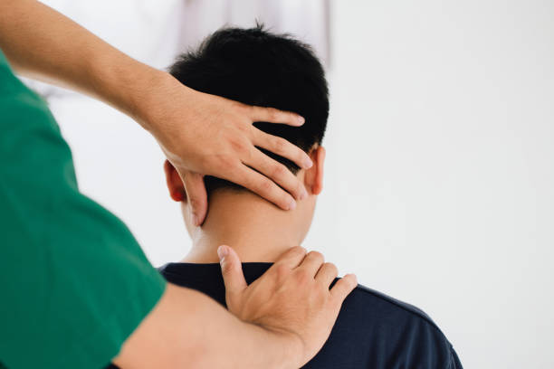physiotherapeut massagetherapeut hält den kopf des männlichen kunden und massiert verspannte nackenmuskulatur das ergebnis einer längeren nutzung von mobiltelefonen. office-syndrom - chiropraktiker fotos stock-fotos und bilder