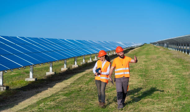 vue d’une centrale solaire avec deux ingénieurs marchant et examinant des panneaux photovoltaïques. concept d’énergie alternative et de son service - solar panel engineer solar power station women photos et images de collection