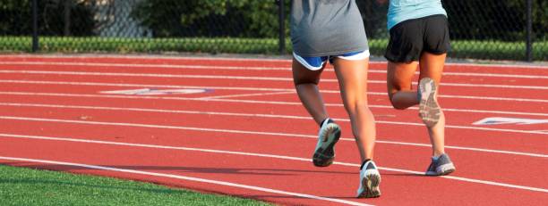 istock Two female runners side by side on a red track 1330201192