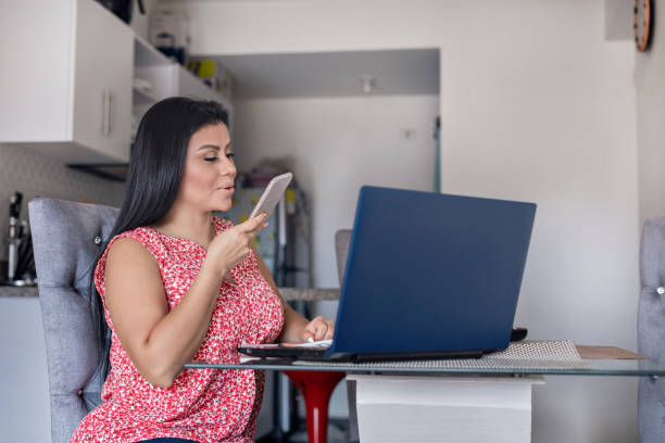 istock Woman working from home talking on cell phone sitting in her dining room 1330202661