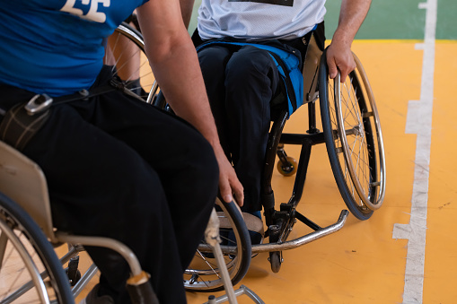 Close up photo of wheelchairs and handicapped war veterans playing basketball on the court. High quality photo