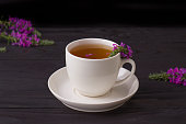 White cup of tea with ivan herbs on a dark wooden background.
