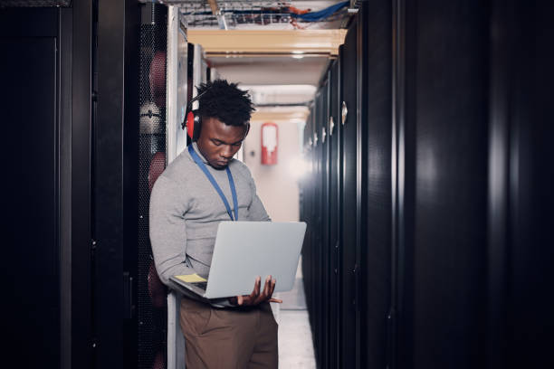 istock Shot of an attractive young man using a laptop at work in a server room 1330215783