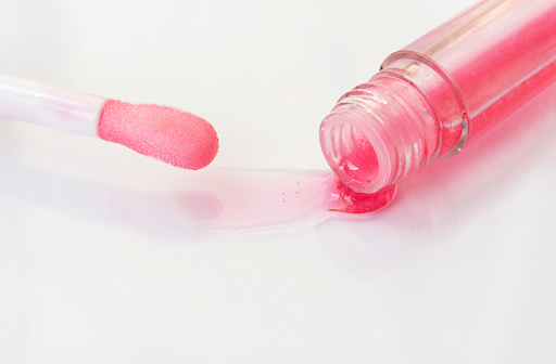 The texture of the lip balm. Oil, transparent liquid flows out of the tube. Image on a white background.