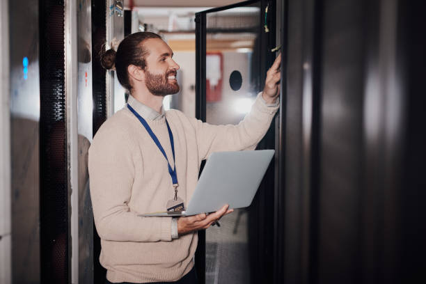 istock Shot of a young man using a laptop in a server room at work 1330216989