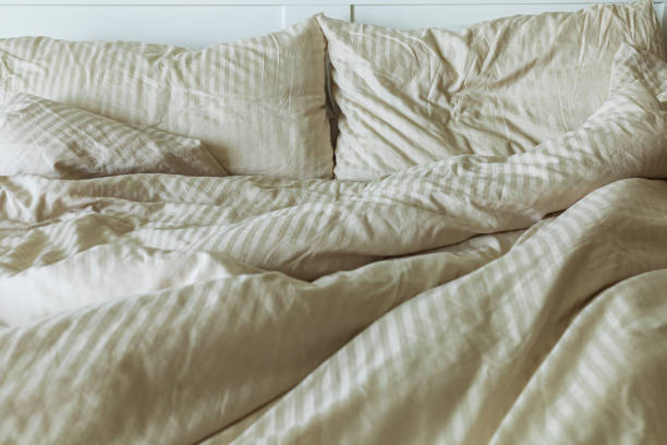 istock An unmade bed with pillows, sheets, and a blanket,  front vew 1330218191