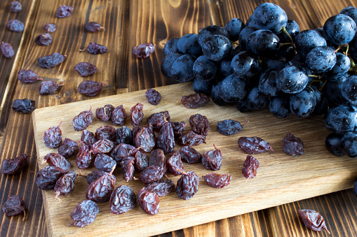 Raisins and blue grapes on the wooden cutting board. Close-up.