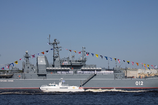 A military metal gray ship during a parade rehearsal on the Neva River on a sunny summer day and copy space in Saint-Petersburg