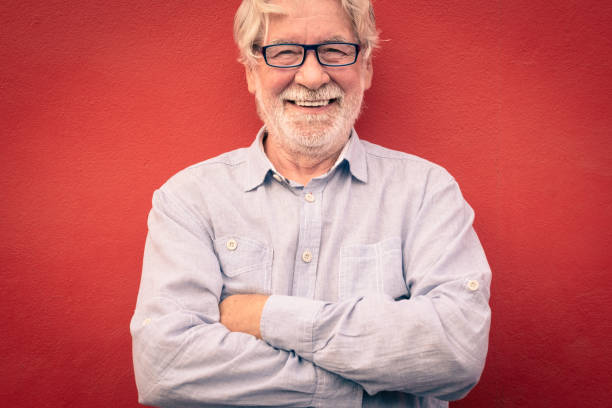 istock Handsome man with crossed arms standing on red background, smiling happily looking at camera, caucasian senior people with white beard and hair 1330222346