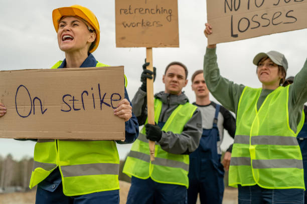 Group of employees in workwear carrying placards during strike Group of employees in workwear carrying placards during strike at quarry strike protest action stock pictures, royalty-free photos & images