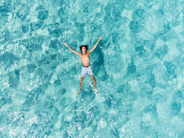 vista aérea de un hombre relajándose en un hermoso mar turquesa transparente - travel luxury aerial view beach fotografías e imágenes de stock