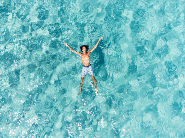 вид с воздуха на человека, отдыхающего в красивом прозрачном бирюзовом море - swimwear caribbean sea beach water стоковые фото и изображения