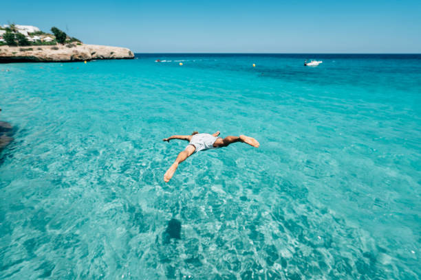 istock Young man is diving in the sea from a cliff 1330224154