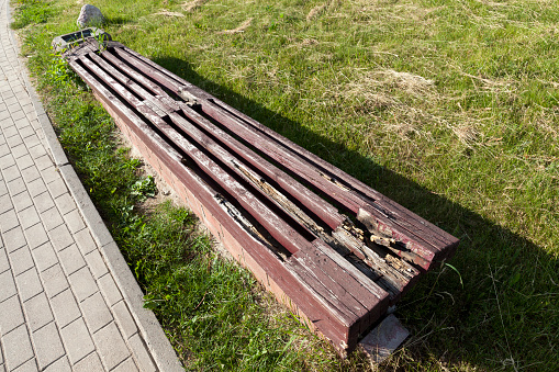 an old rotting wooden bench in the park, a broken and collapsing wooden bench