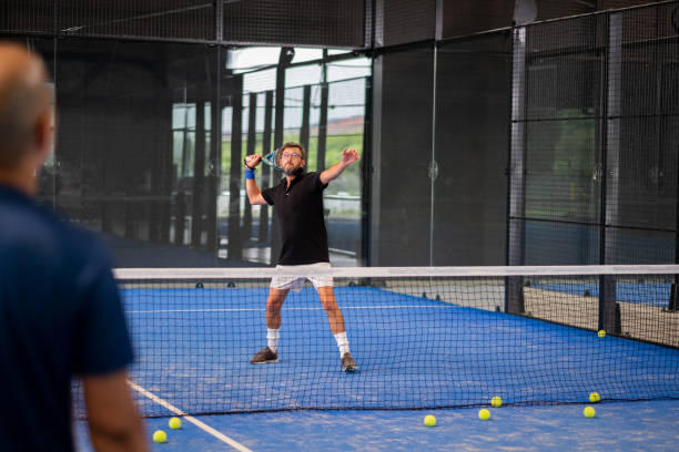 istock Monitor teaching padel class to man, his student - Trainer teaches boy how to play padel on indoor tennis court 1330229225