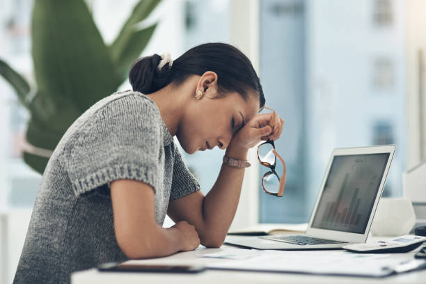 foto de una joven empresaria que mira estresada mientras trabaja en una oficina - agotamiento fotografías e imágenes de stock