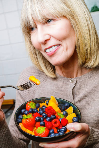 istock Attractive senior woman with fruit bowl 1330230063