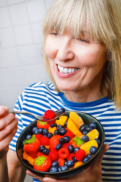 istock Attractive senior woman with fruit bowl 1330230497