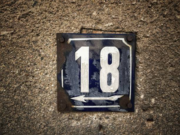 istock Old rusty metal sign with number 18 hung on a brick wall 1330233232