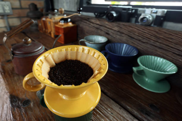 istock Pouring coffee from a pot through a paper filter on a cup at table background hand coffee grinder and more dripper colorful and film camera 24 / 159 1330233328