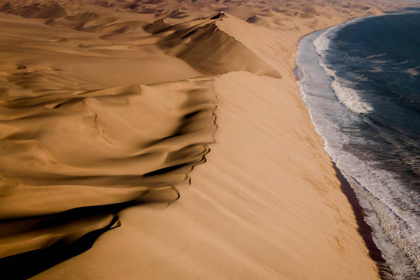 Aerial View of Sandwich Harbour Near Walvis Bay in Namibia, Africa Aerial view of Sandwich Harbour, where the Namib desert meets the Atlantic coast, near Walvis Bay in Namibia, Africa. sand dune photos stock pictures, royalty-free photos & images