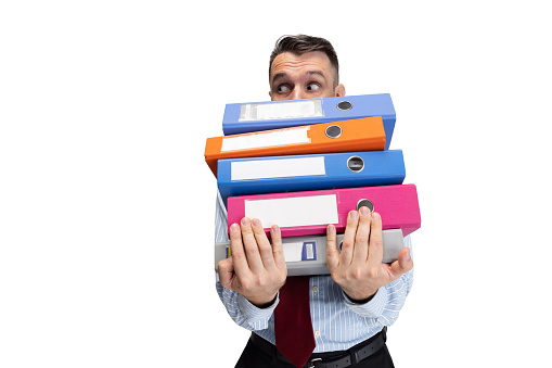 One young Caucasian man, office worker with lots of folders in hands isolated over white studio background. Concept of human emotions, facial expression, sales, ad