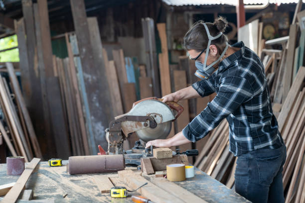 istock Male carpenter wearing safety dust filter mask at work. woodworker using circular saw cutting piece of wood at woodwork workshop 1330236758