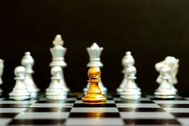 istock Gold pawn in chess game face with the another silver team on black background (Concept for company strategy, business victory or decision) 1330239614